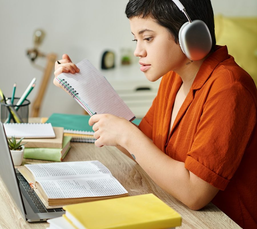 vertical shot of young attractive student with headphones studying hard and looking at laptop